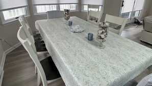 Ein Esszimmer mit einem für vier Personen gedeckten Tisch, weißen Stühlen und einer weißen Tischdecke.