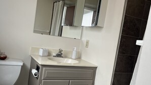 Ein Badezimmer mit Toilette, Waschbecken, Spiegel und Duschbereich.