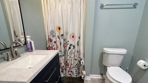 Een badkamer met douchegordijn, toilet, wastafel en handdoekhouder.