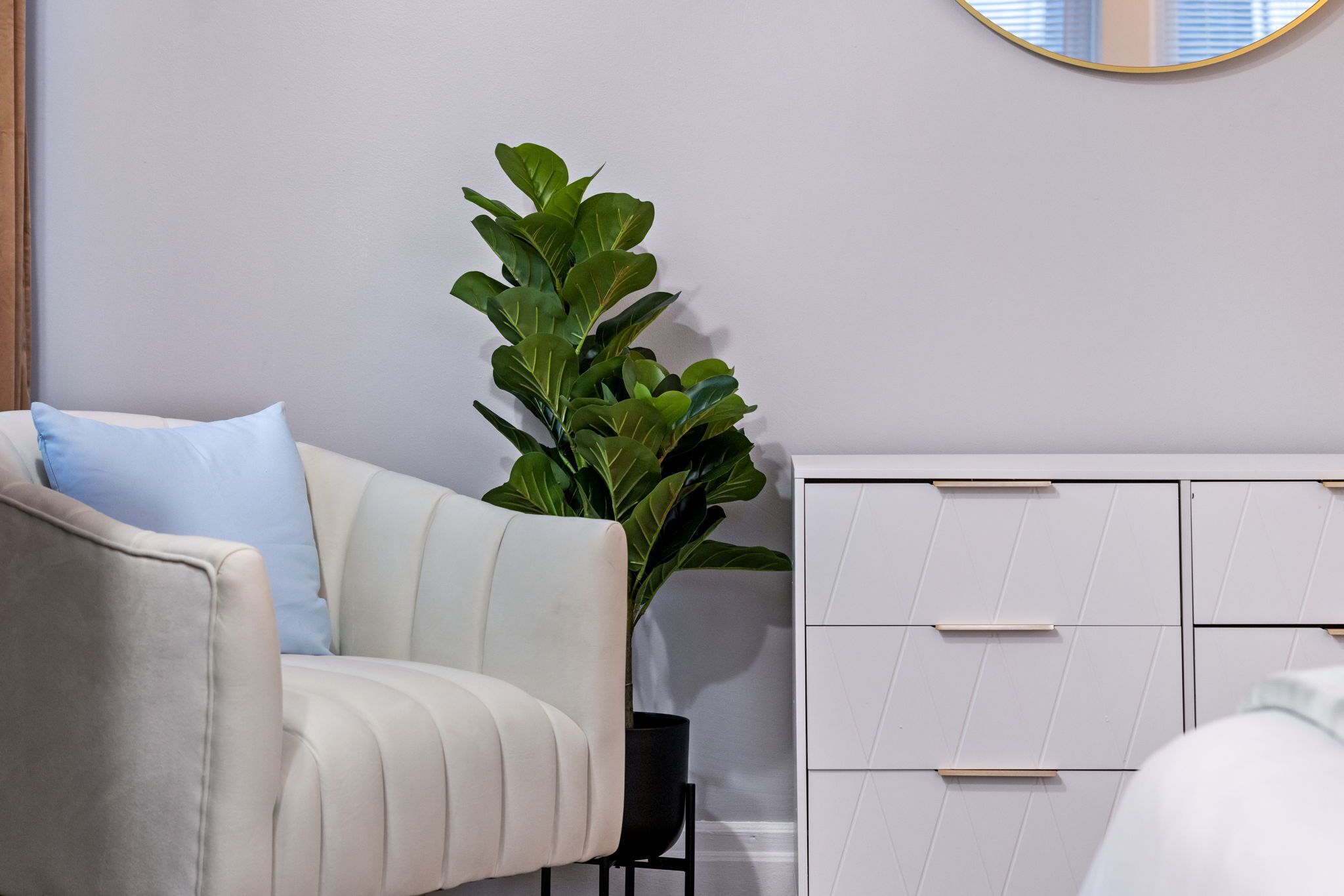 Une pièce avec un canapé blanc, une plante en pot et une commode blanche dotée de tiroirs.