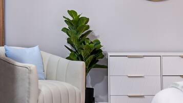 Une pièce avec un canapé blanc, une plante en pot et une commode blanche dotée de tiroirs.