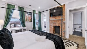 Quarto moderno com uma cama grande, lareira de tijolos e vista para o exterior.
