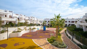 A residential area with white buildings, a playground, and a paved walkway.