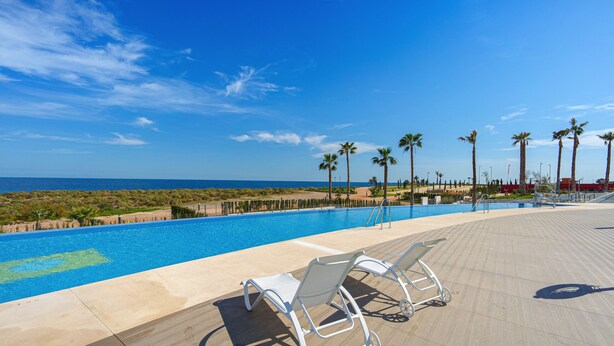 A poolside area with lounge chairs and a view of the ocean.