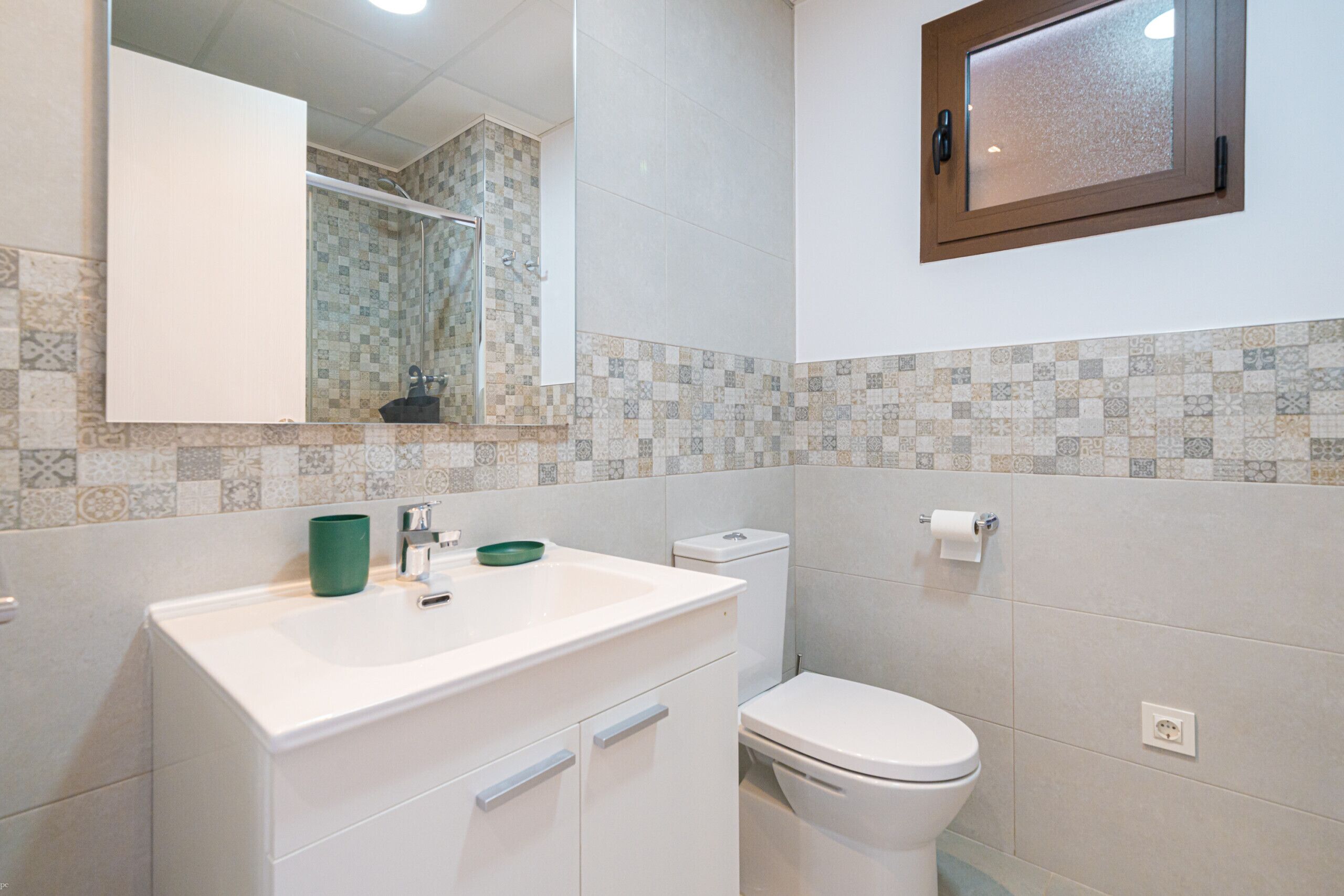 A bathroom with a white sink, green bowl, and a toilet.