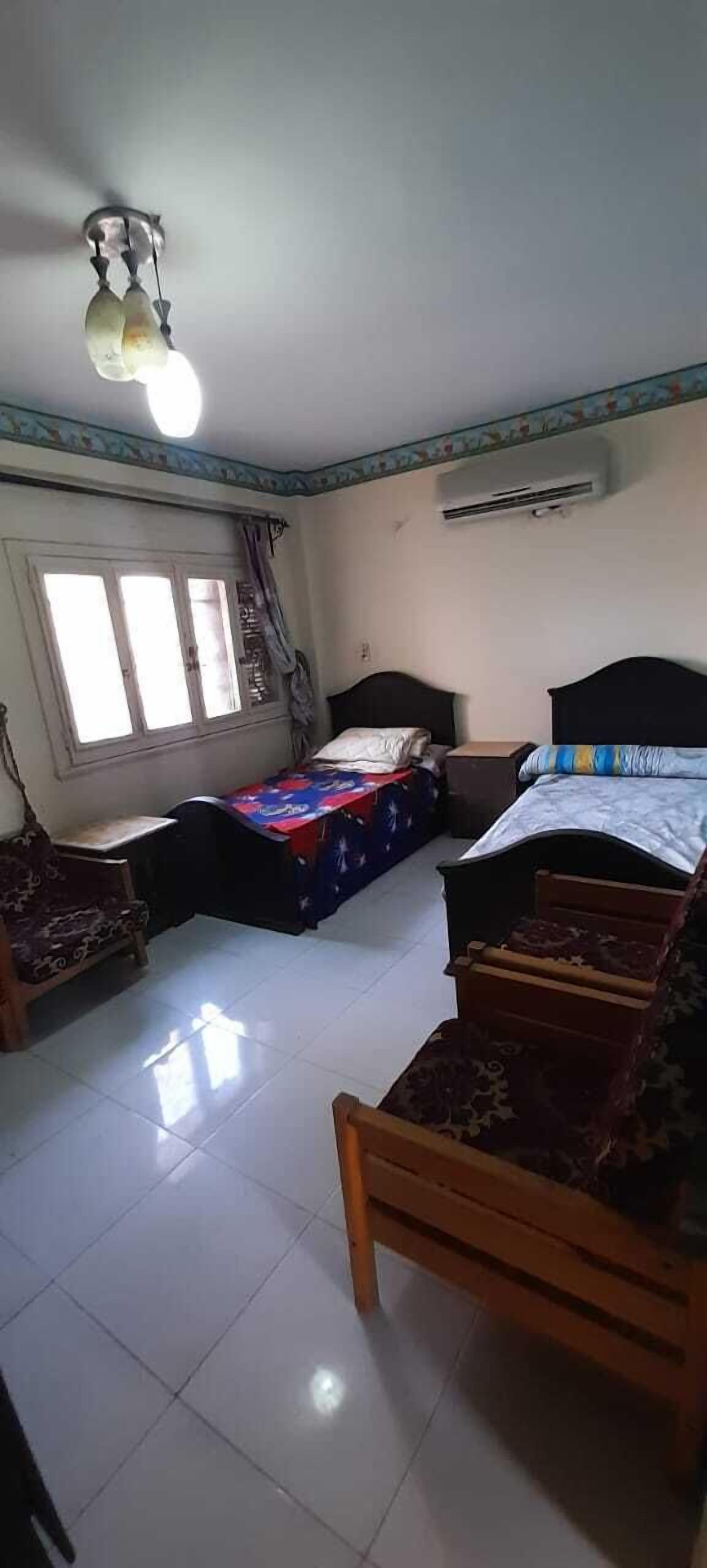 Una habitación con dos camas, una ventana con cortinas, un ventilador de techo y un equipo de aire acondicionado.