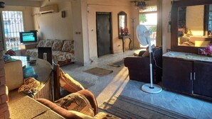 A spacious living room with a sofa set, a dining table, and a TV. There is a fan, a fireplace, and a door leading to another room. - Villa Dr mohamed (Alexandria)