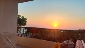 A balcony with a view of the sunset, a folding chair, a sofa, and a small table. - Villa Dr mohamed (Alexandria)