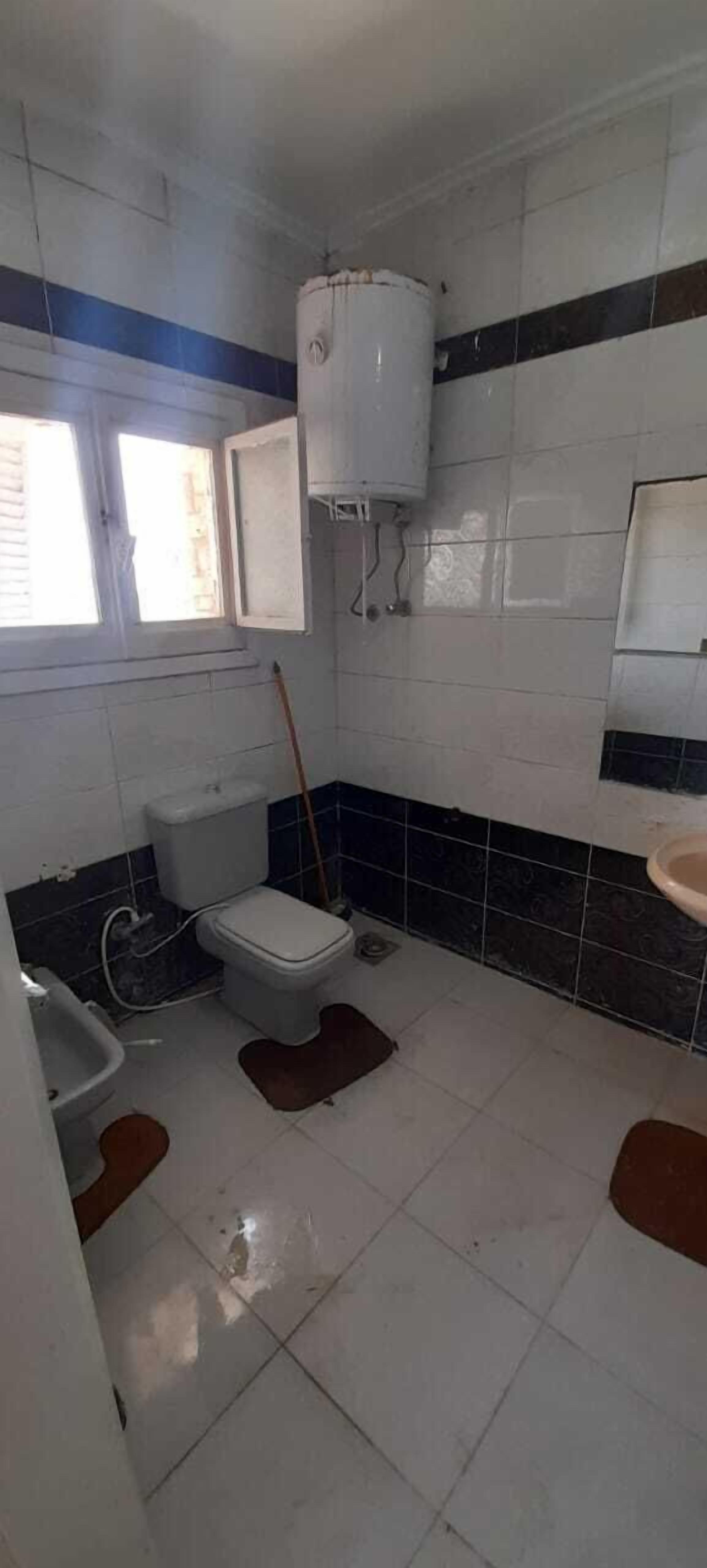 Un baño pequeño y funcional, con inodoro, lavabo y ventana.