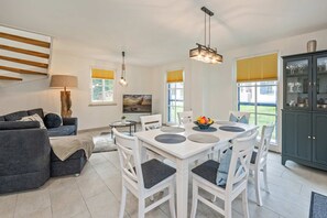 Un salon moderne comprenant un coin repas, un canapé, une lampe et un meuble.