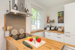 Une cuisine moderne avec un plan de travail en bois, une cuisinière encastrée et une fenêtre donnant sur les arbres.