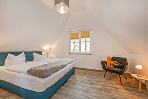 Une chambre à coucher avec un lit, une chaise, une lampe et une fenêtre.
