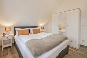 Une chambre à coucher comprenant un lit, des lampes de chevet, une armoire et une table de chevet.