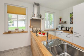 Une cuisine moderne dotée d’un évier en acier inoxydable, de plans de travail en bois et d’une cuisinière encastrée.