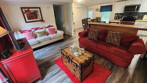 Ein Wohnzimmer mit einem roten Sofa, einem weißen Sofa, einem Holztisch und einer roten Kommode.