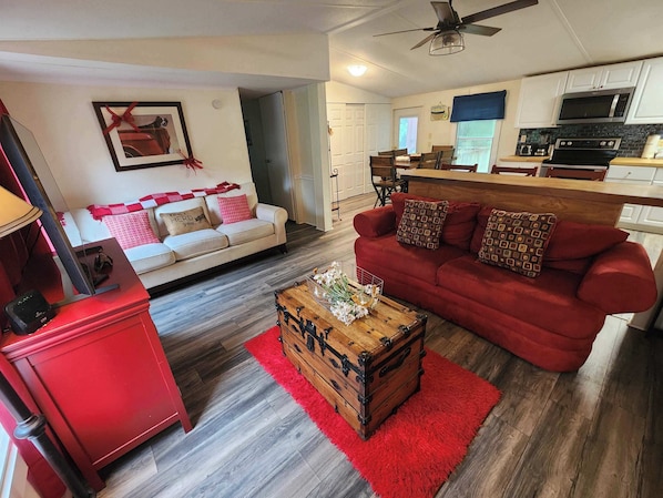 A living room with a red sofa, a white sofa, a wooden coffee table, and a red cabinet.