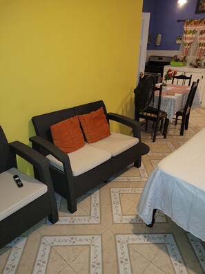 Ein Essbereich mit Tisch für zwei Personen, einer Couch mit Kissen und einem Sessel.
