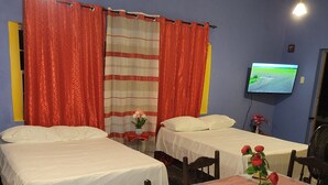 Una habitación con dos camas, una mesa de comedor con sillas, un televisor en la pared y un piso con diseño.