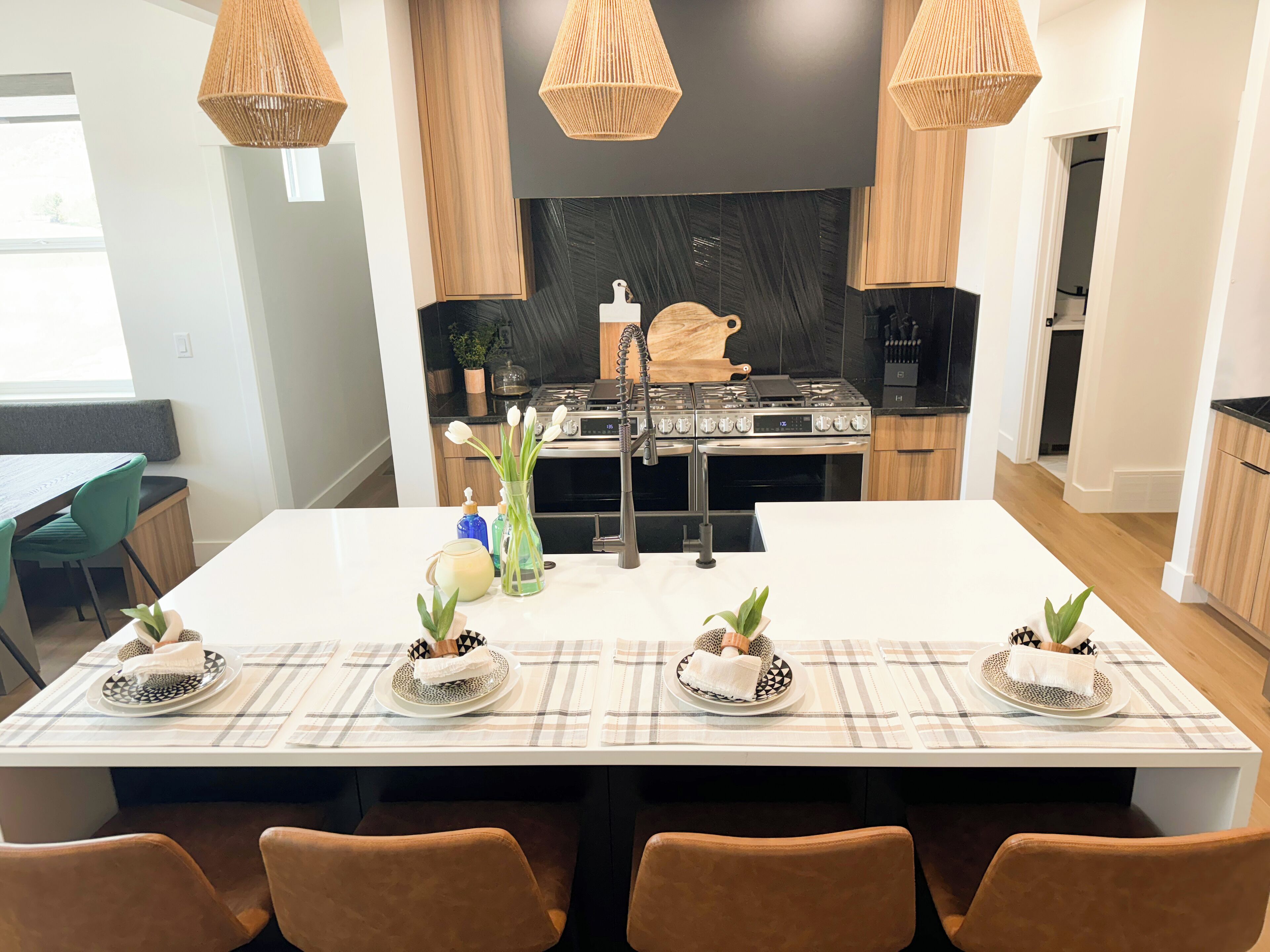 A modern kitchen with a central island, black backsplash, and wooden cabinets.