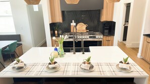Een moderne keuken met een centraal eiland, een zwarte spatwand en houten keukenkastjes.