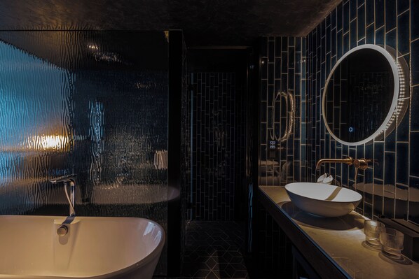 Une salle de bain moderne avec une baignoire sur pieds, un miroir rond et un lavabo doté d’un récipient en verre.