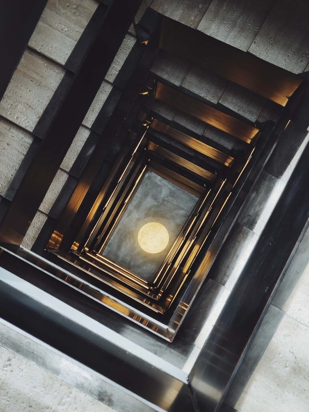 A modern elevator interior with a circular light fixture and metallic accents.