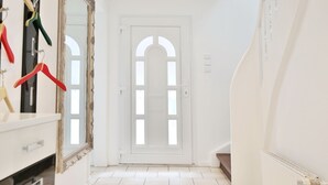 Ein Flur mit einer weißen Tür, einem Spiegel und einer Heizung.