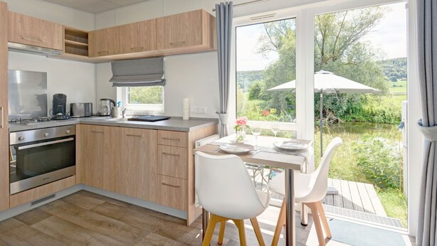 Une cuisine moderne avec des meubles en bois, un four encastré et un coin repas comprenant une table et des chaises.