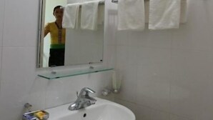 A bathroom with a white sink, a mirror, and two towels hanging on a towel rack.