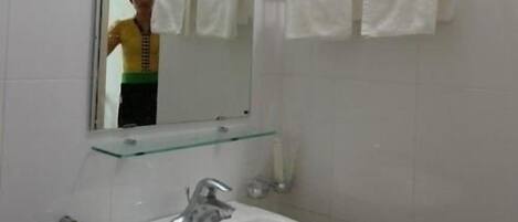 A bathroom with a white sink, a mirror, and two towels hanging on a towel rack.