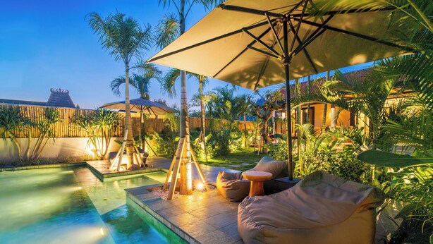 A poolside area with a lounge chair, a table, and a tiki torch. - Ibumah Villa Bingin (Pecatu)