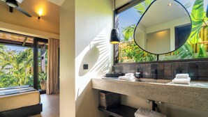 A modern bathroom with a large mirror, a granite countertop, and a view of tropical plants. - Ibumah Villa Bingin (Pecatu)