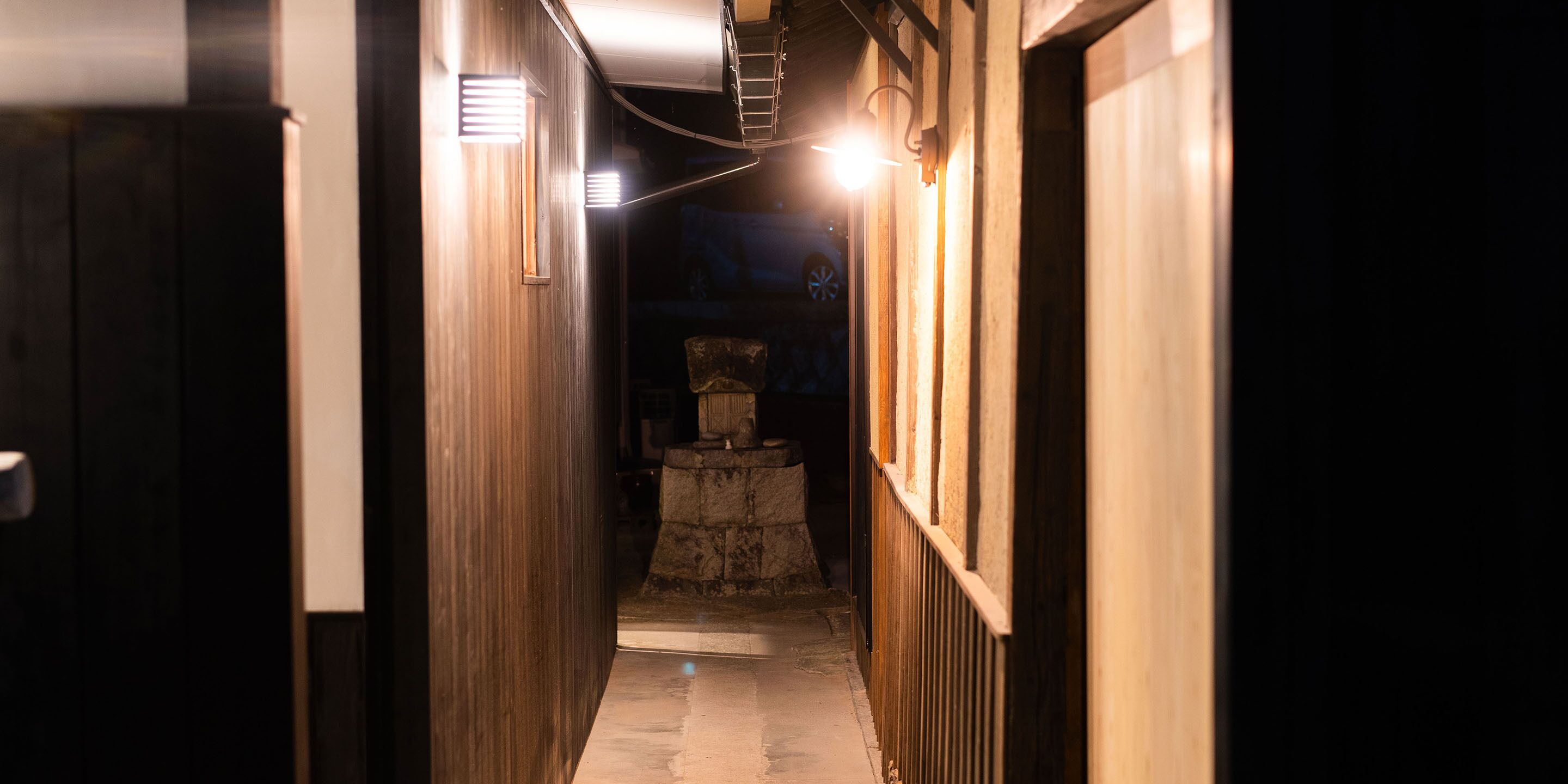 A narrow hallway with wooden walls and a stone pedestal in the center.