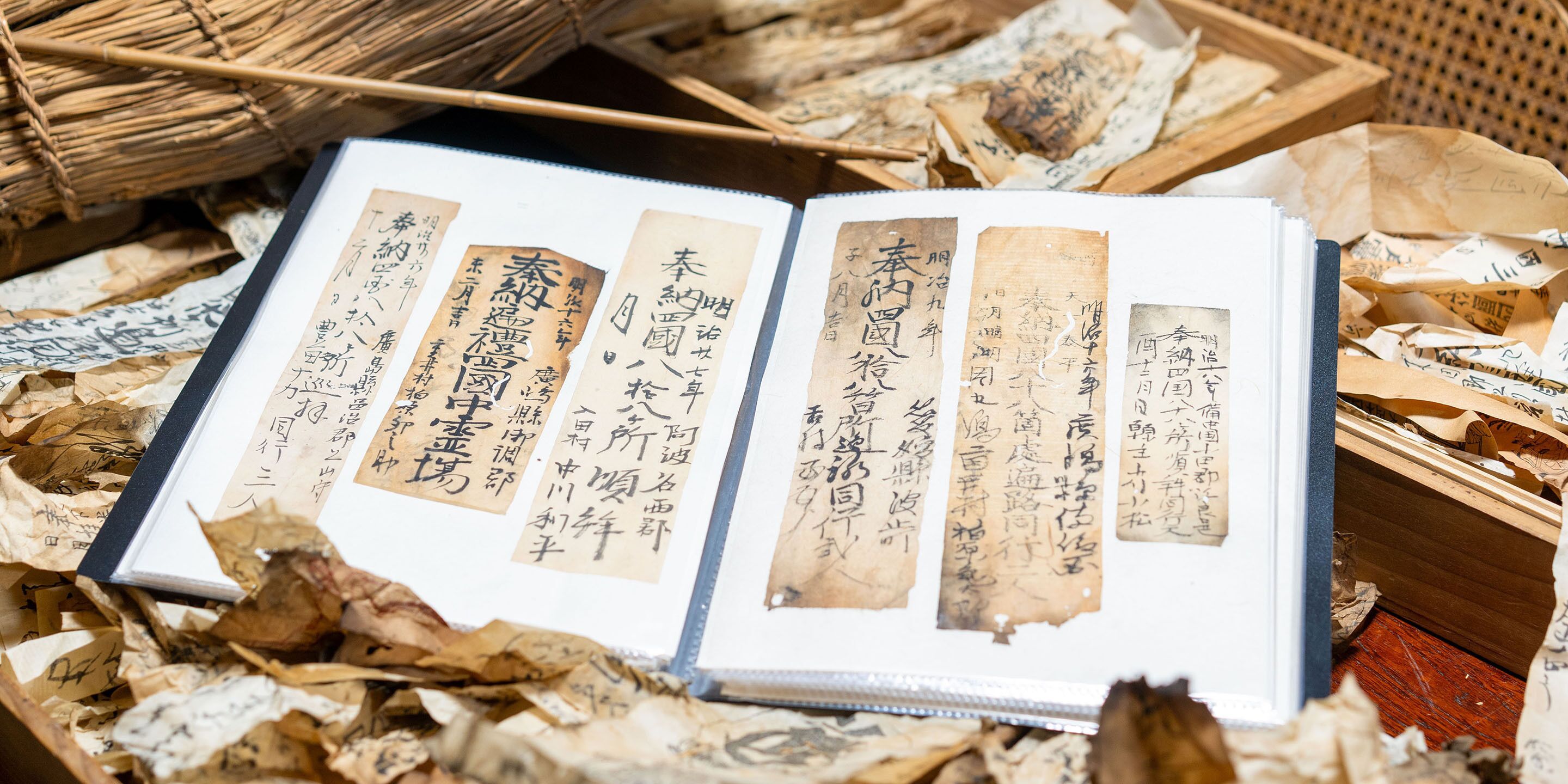 An open book with Japanese text, surrounded by crumpled paper and a woven basket.