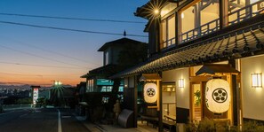 A traditional Japanese building with a wooden exterior and tiled roof, featuring large windows and a lantern outside. - OnyadoTakayanagi (Takamatsu)