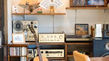A music studio with vintage audio equipment, a guitar, and a bookshelf with CDs.