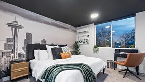 A modern bedroom with a bed, a desk, and a chair. - The Emerald Den (Seattle)