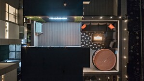 A rooftop terrace with a seating area, a small table, and a decorative wall. - The Emerald Den (Seattle)