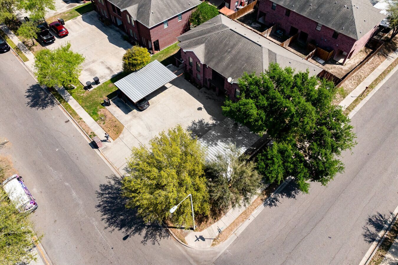 Vue aérienne d’un quartier résidentiel avec des immeubles en briques, un parking et un grand arbre.