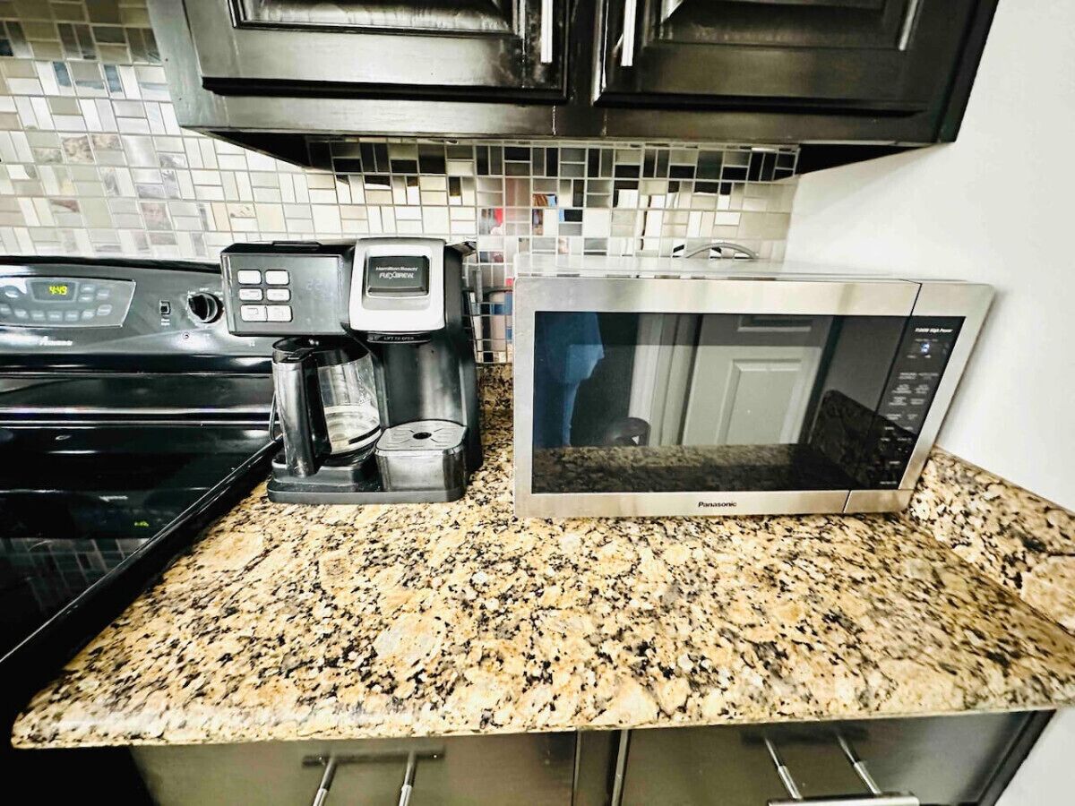 A kitchen with a coffee maker, microwave, and stainless steel appliances.
