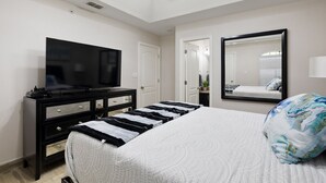 A modern bedroom with a large bed, a television on a black dresser, a mirror, and a skylight. - Sharyland Townhome - 2/2.5 bedrooms with patio in McAllen (McAllen)