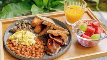 Un plateau de petit-déjeuner avec des œufs, des haricots, du bacon, des toasts et un saladier de fruits.