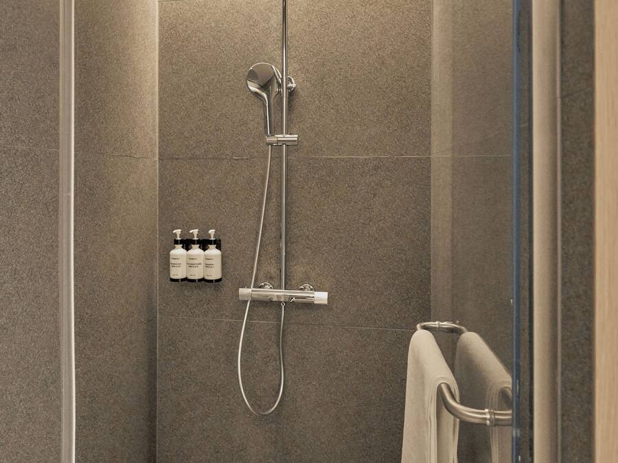 Una ducha moderna con cabezal de ducha de mano y panel de control en la pared.