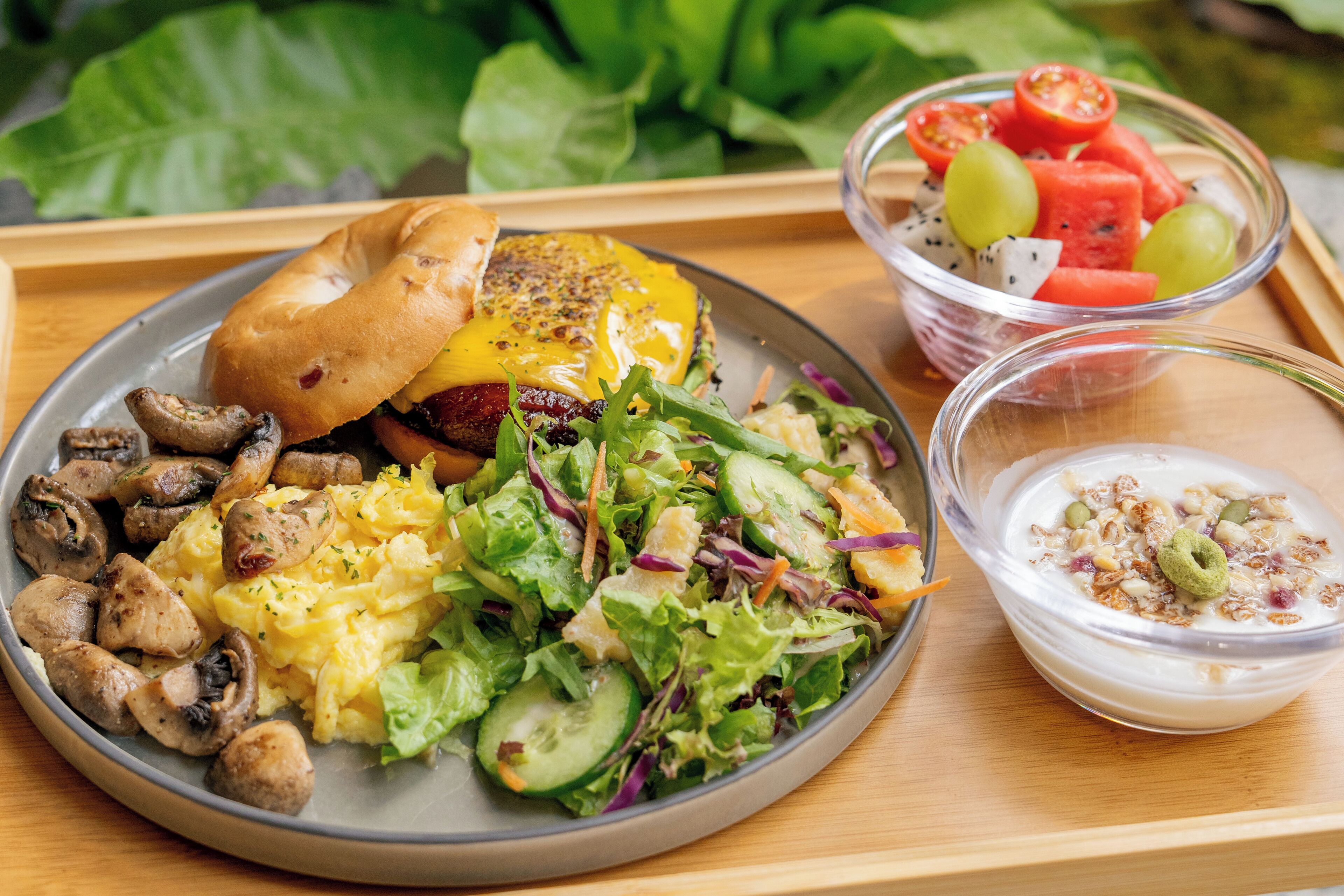 Ein Tablett mit einem Burger, Salat und einer Fruchtschale.