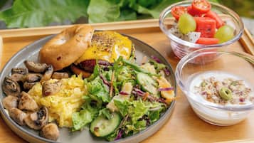 A meal tray with a burger, salad, and fruit bowl.