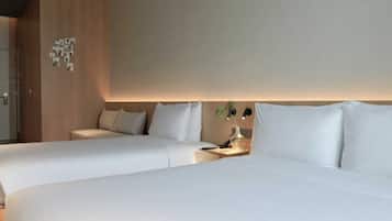 Une chambre d’hôtel avec deux lits, une table de chevet avec une lampe et un luminaire fixé au mur.