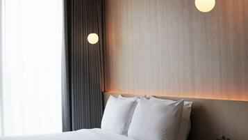 Habitación de hotel moderna con una cama grande, una cortina oscura, una lámpara redonda y una planta.