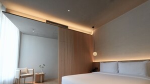A modern hotel room with a large bed, a seating area with a chair and a small table, and a large window providing natural light. - The Yard Boutique Hotel Shanghai  (Shanghai)