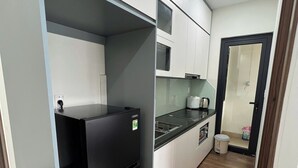 A compact kitchen with a black refrigerator, white cabinets, a microwave, and a sink.