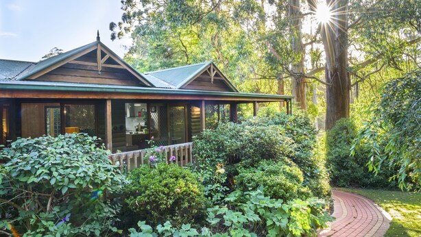 A wooden house with a green roof, surrounded by lush greenery and a brick pathway. - Botanica Retreat - Village Spa & Stay (Olinda)